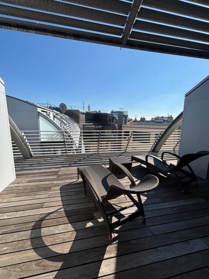 Sonnige Dachterrasse mit Holzdeck und Liegestühlen, ideal zum Entspannen mit Weitblick.