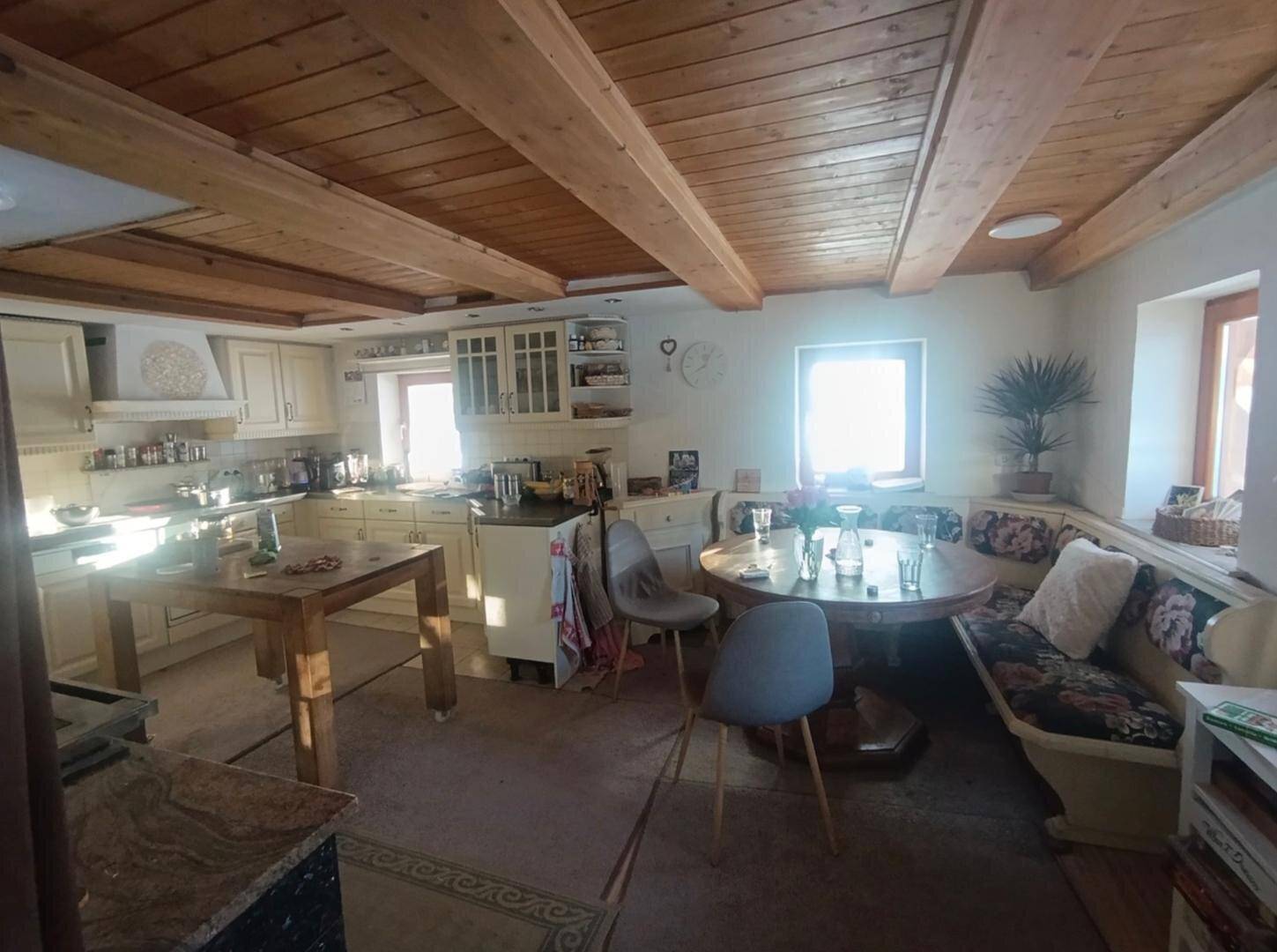 Rustikale Küche mit Holzbalkendecke, Einbauküche und einem Essbereich mit Eckbank.
