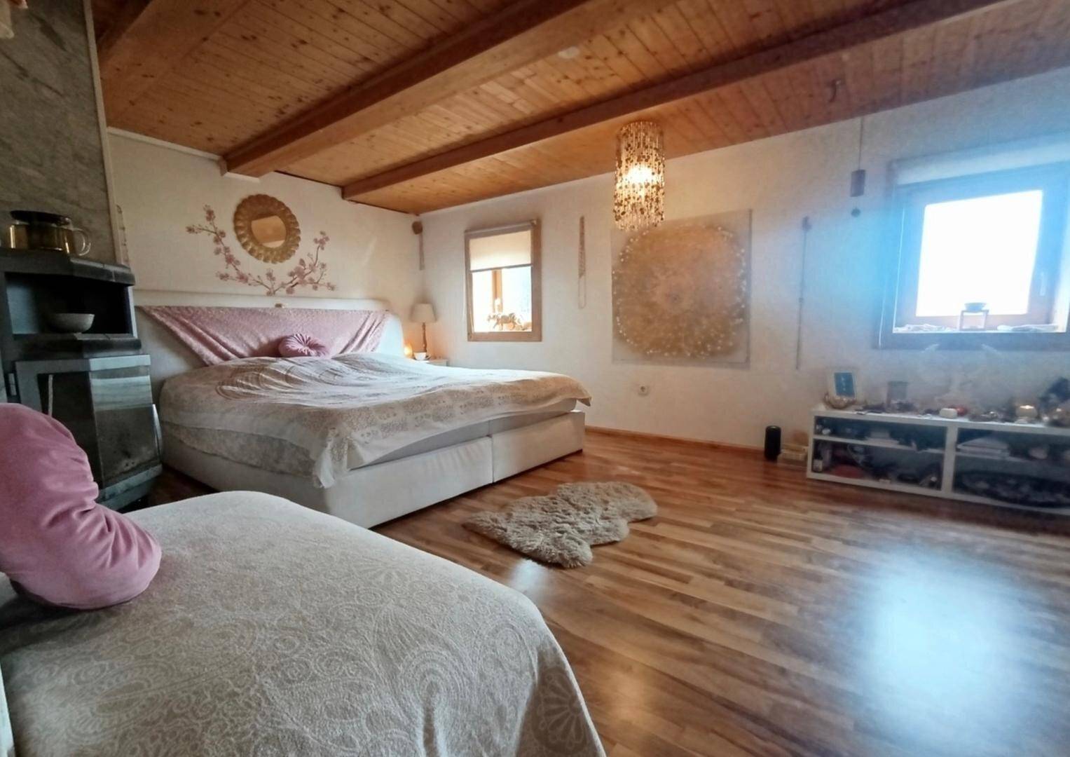 Geräumiges Schlafzimmer mit Holzbalkendecke, Doppelbett und Holzboden, hell und freundlich gestaltet.