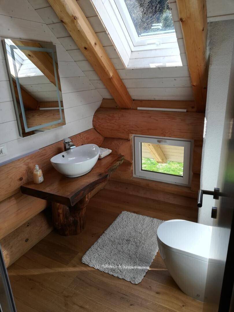 Helles Badezimmer mit Holzwaschtisch, Aufsatzwaschbecken, Toilette und Dachfenster.