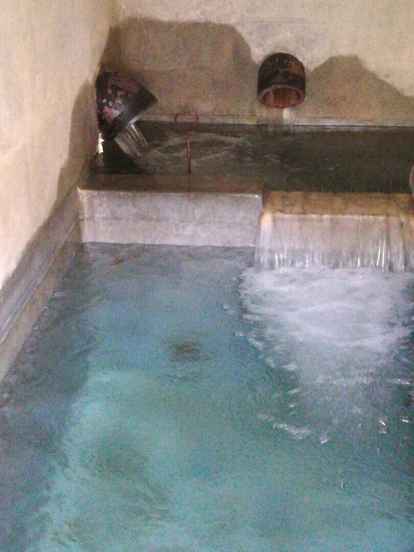 Kleines Tauchbecken mit fließendem Wasser in einem rustikalen Raum.