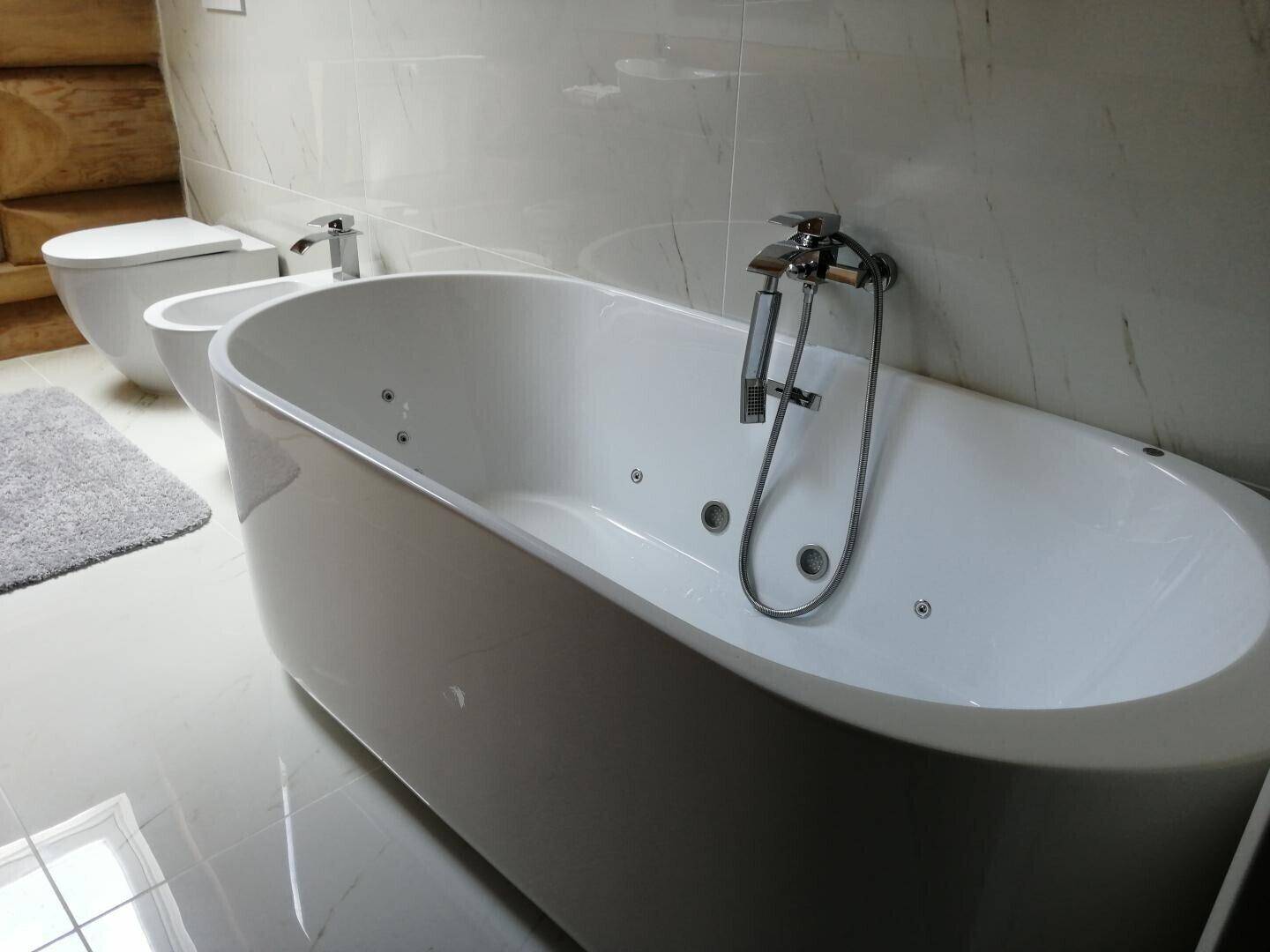 Luxuriöses Badezimmer mit freistehender Badewanne, Bidet und eleganten Fliesen.