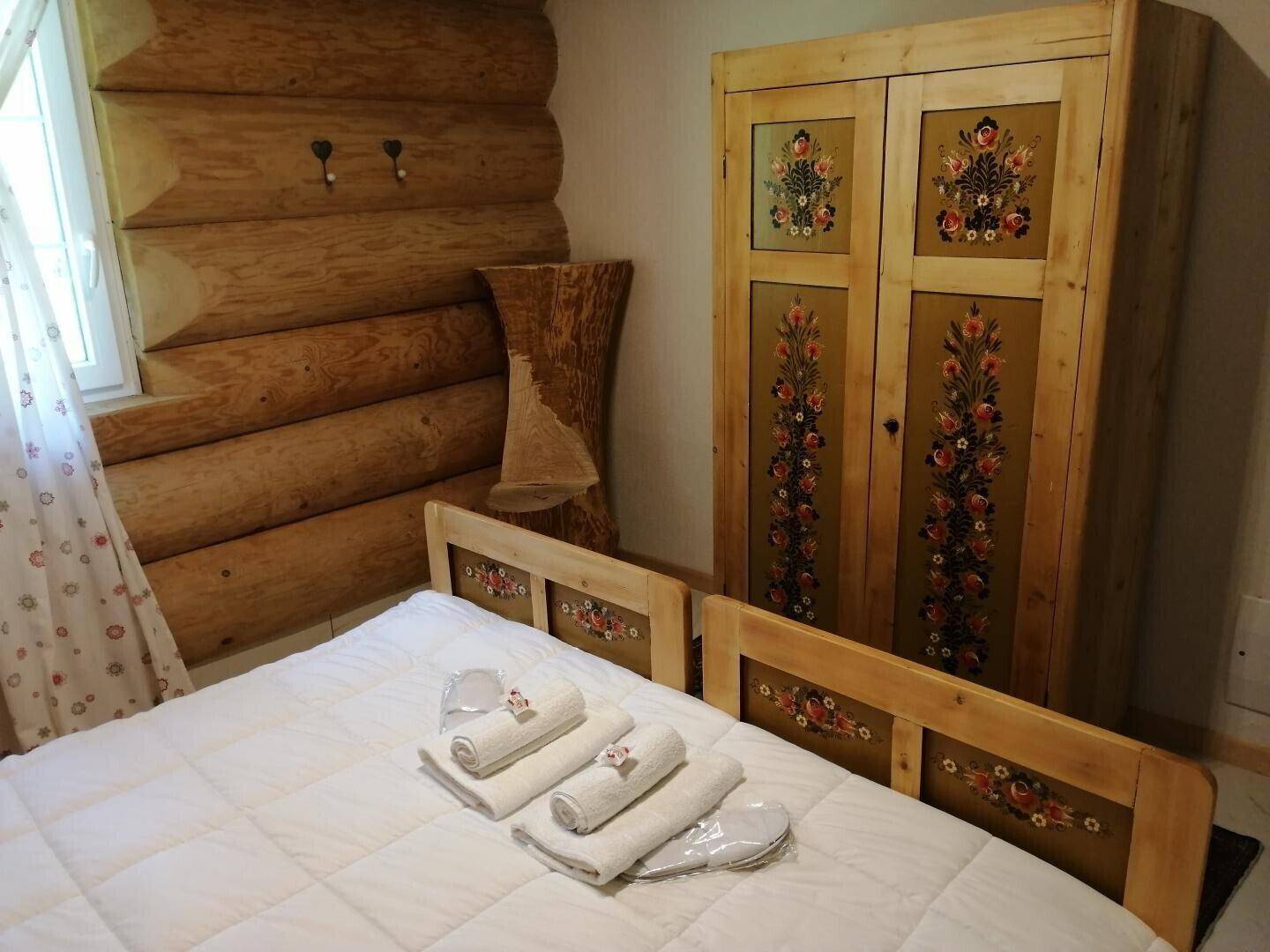 Schlafzimmer mit handbemaltem Holzschrank und rustikalen Holzwänden, einladend und gemütlich.