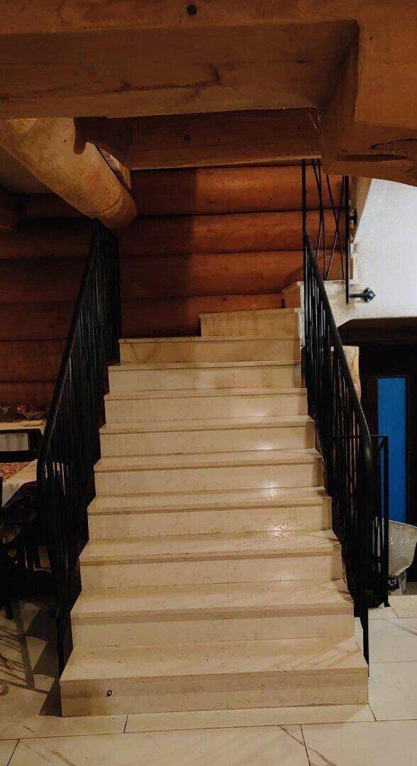 Elegante Treppe mit Marmorstufen und schmiedeeisernem Geländer in rustikalem Ambiente.