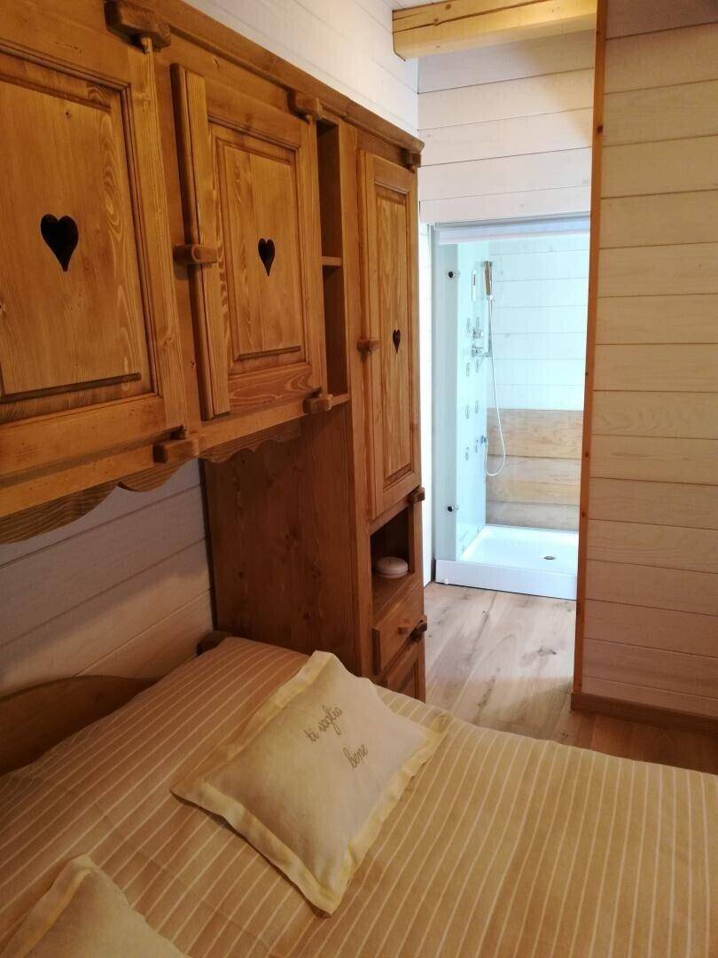 Schlafzimmer mit traditionellen Holzmöbeln und direktem Zugang zu einem modernen Duschbad.
