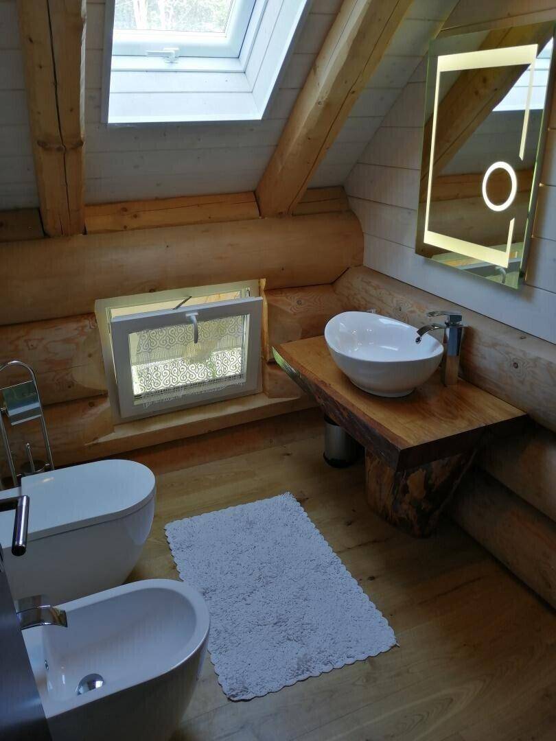 Modernes Badezimmer mit Holzwaschtisch, Aufsatzwaschbecken, Bidet und Dachfenster für viel Licht.
