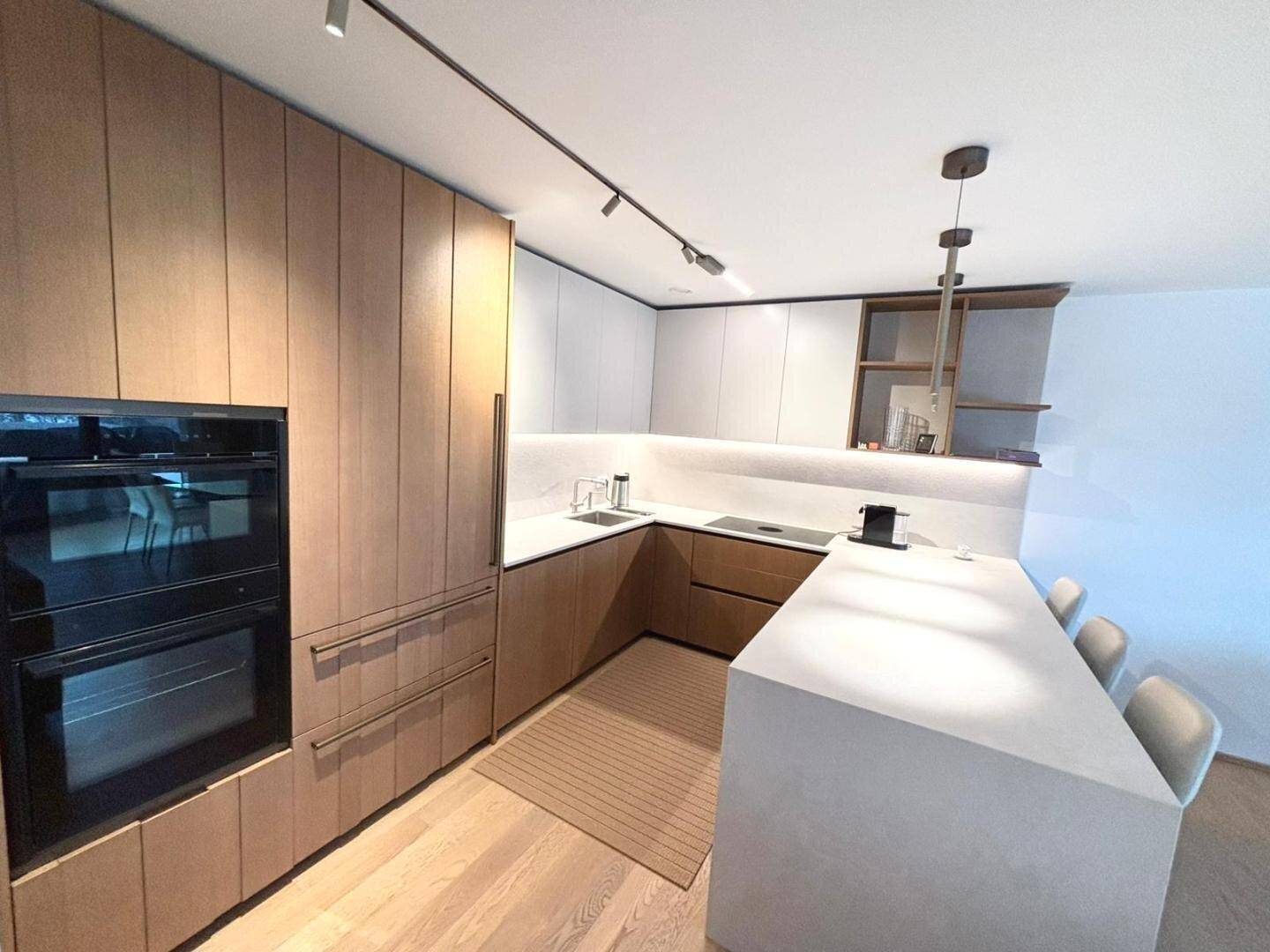 Geräumige moderne Küche mit Holzfronten, doppelten Einbauöfen und großer Kochinsel.