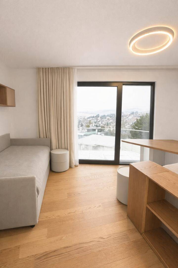 Helles Schlafzimmer mit Einzelbett, Nachttischen und großem Fenster mit weitem Ausblick.