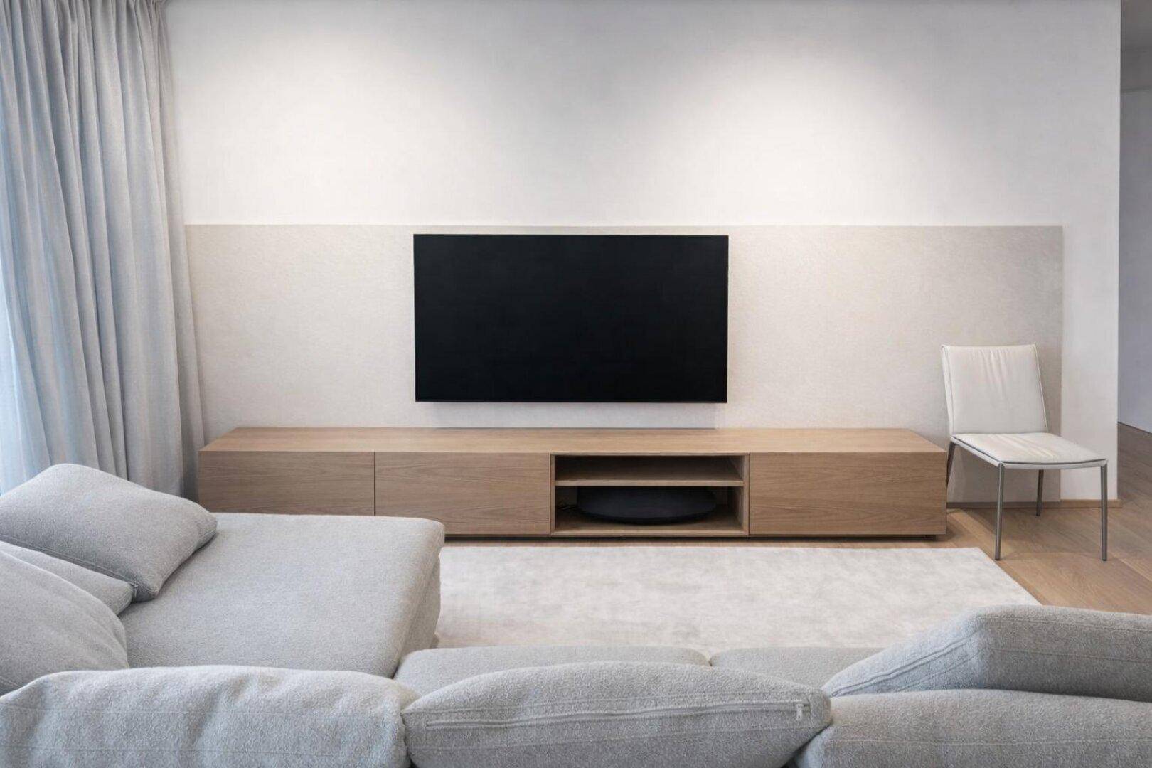 Minimalistischer Wohnbereich mit wandmontiertem Fernseher und elegantem Holz-Medienmöbel.