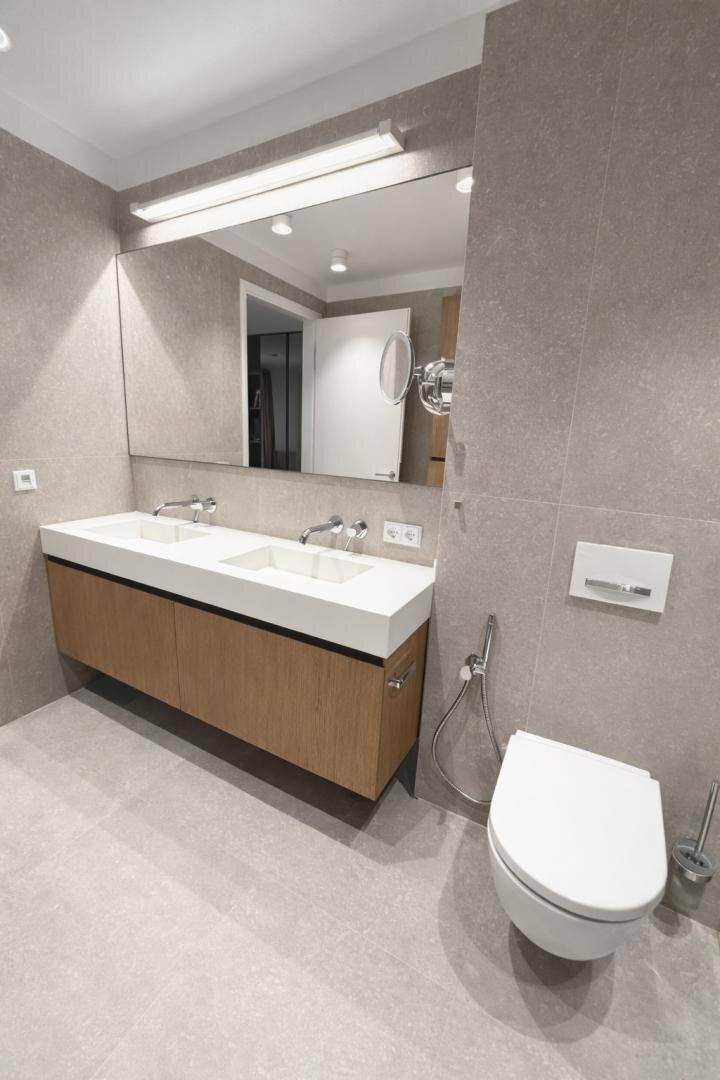 Elegantes Badezimmer mit Doppelwaschbecken, großem Spiegel und wandhängendem WC mit Bidetfunktion.