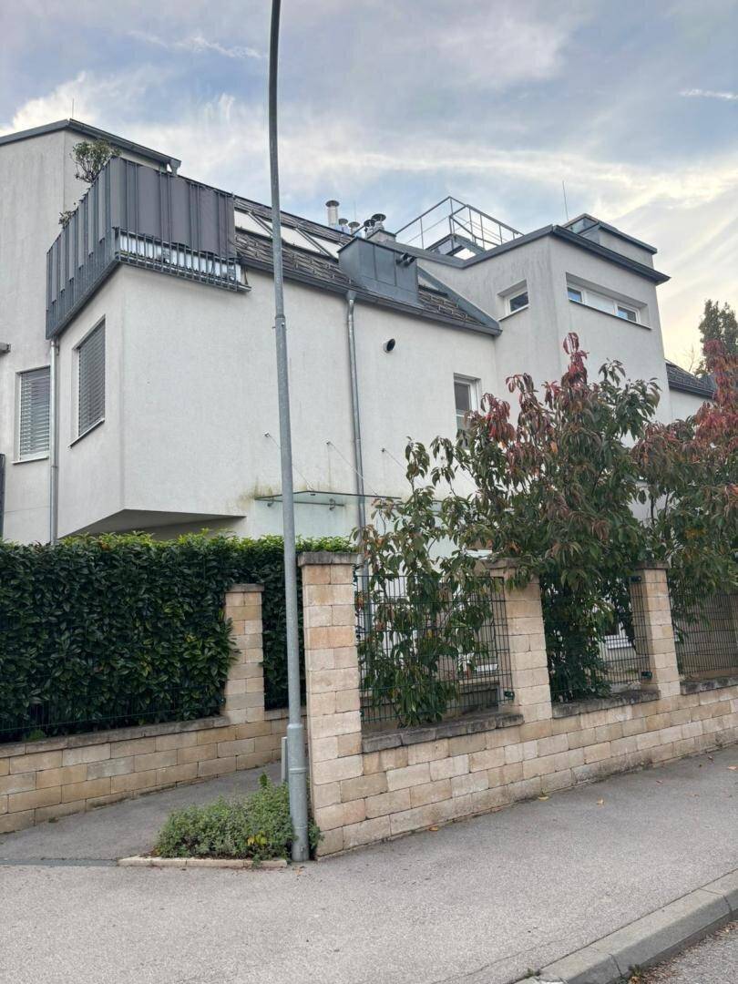 Moderne Wohnanlage mit weißer Fassade, Dachterrassen und grüner Hecke.