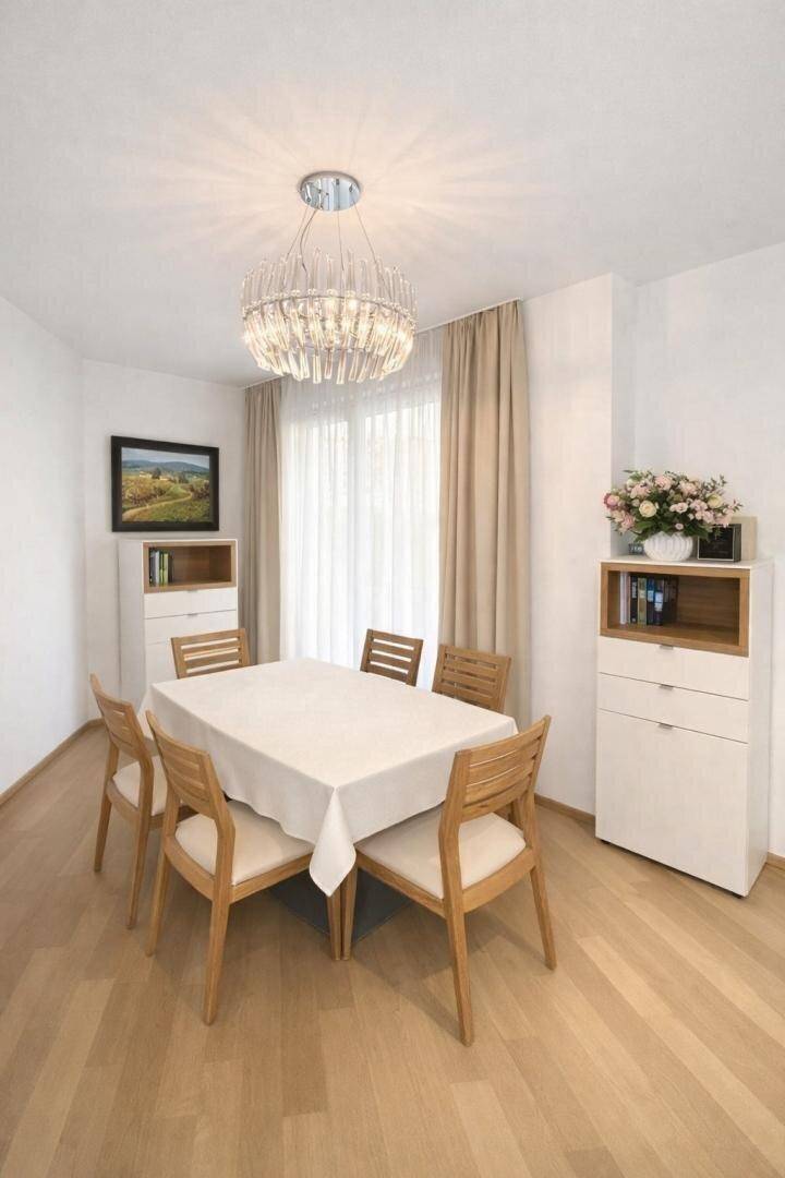 Heller Essbereich mit Holztisch, Stühlen und einem eleganten Kronleuchter.