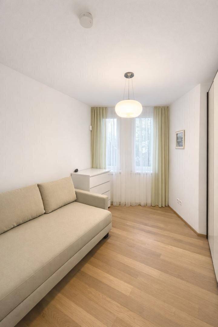 Gemütliches Schlafzimmer mit Einzelbett, Holzboden und Fenster mit Vorhängen.