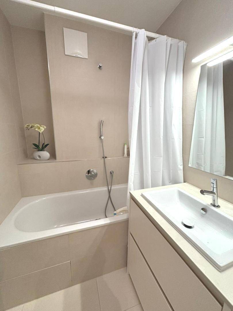 Modernes Badezimmer mit Badewanne, Duschvorhang und Einzelwaschbecken.