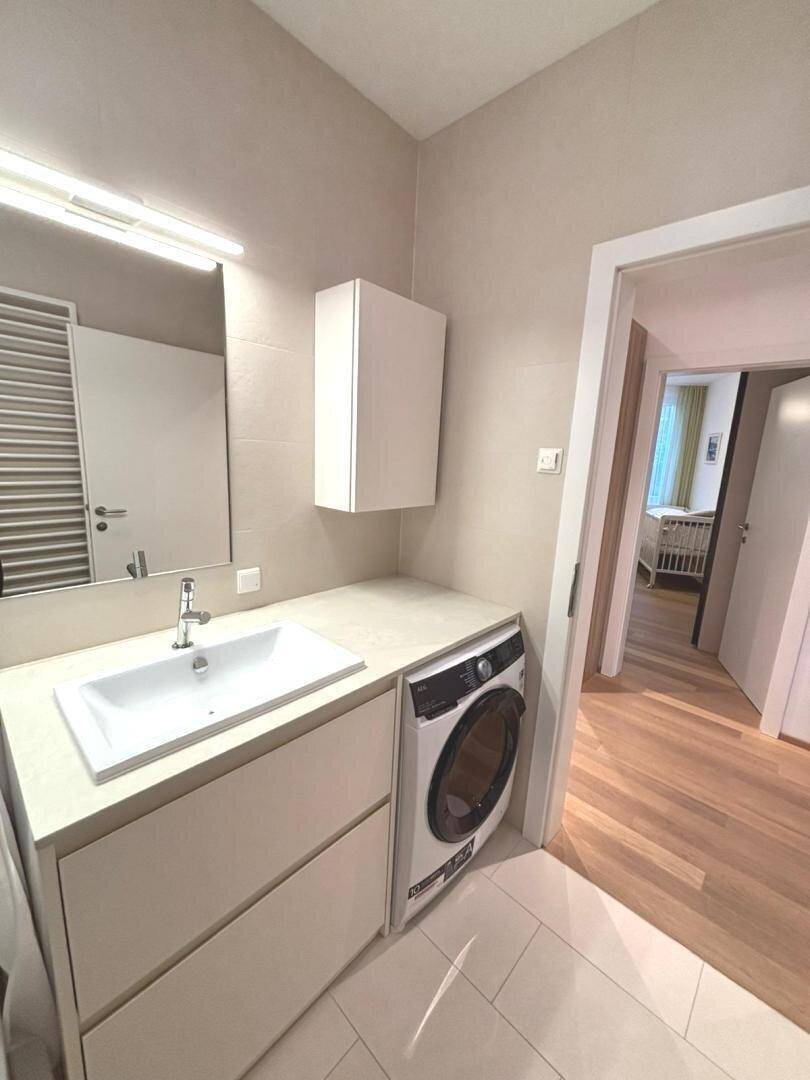 Praktischer Waschraum mit Waschmaschine, Waschbecken und Spiegelschrank.