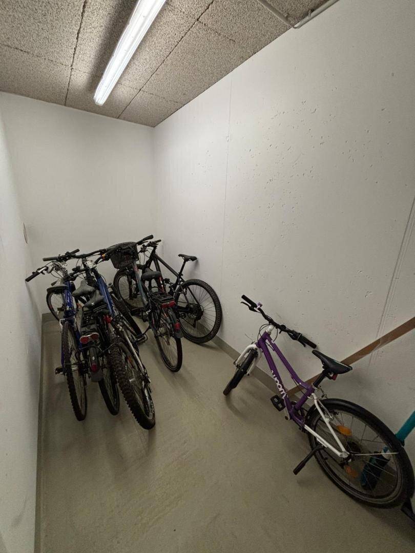 Fahrradraum im Keller mit mehreren abgestellten Fahrrädern und Beleuchtung.