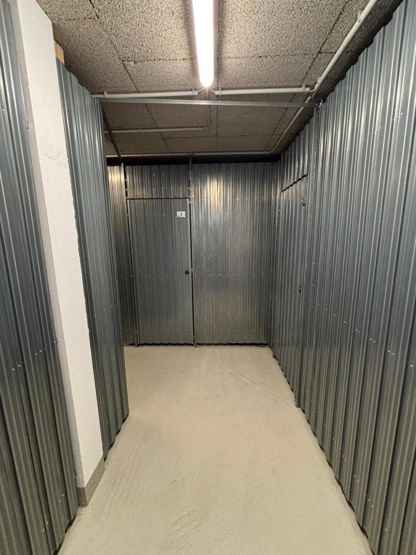 Kellerabteil mit Metallwänden und abschließbaren Türen für zusätzlichen Stauraum.