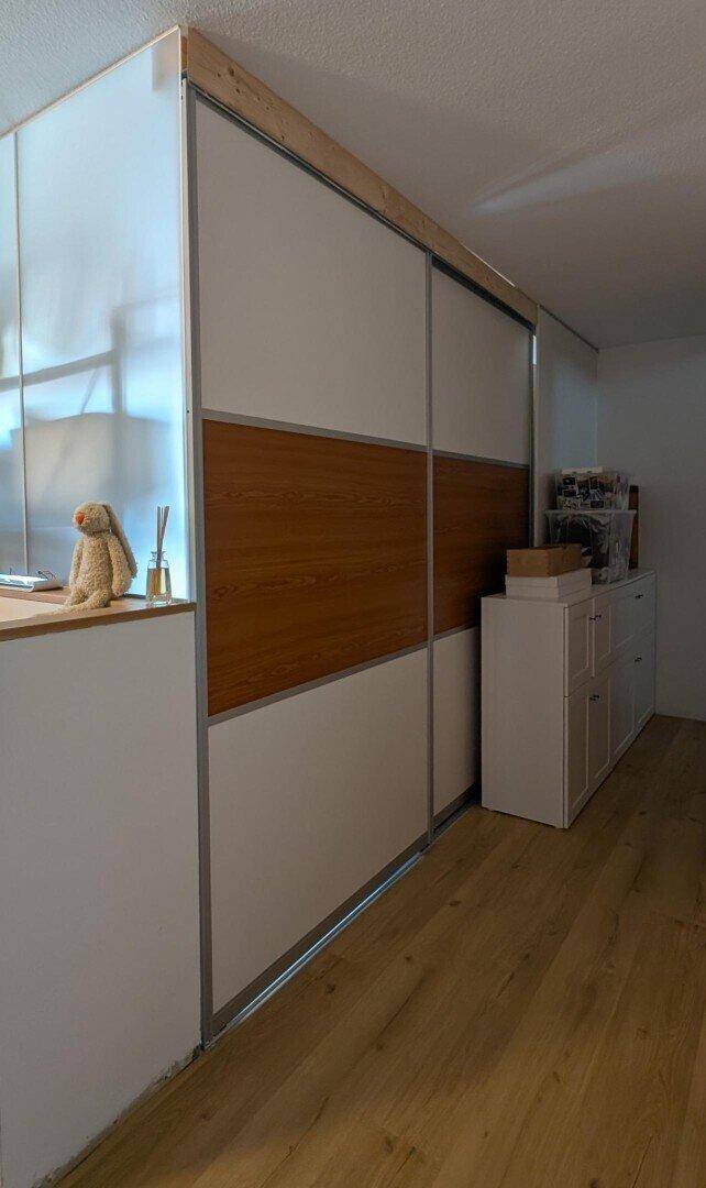 Moderner Einbauschrank mit Schiebetüren und Holzelementen im Flurbereich.