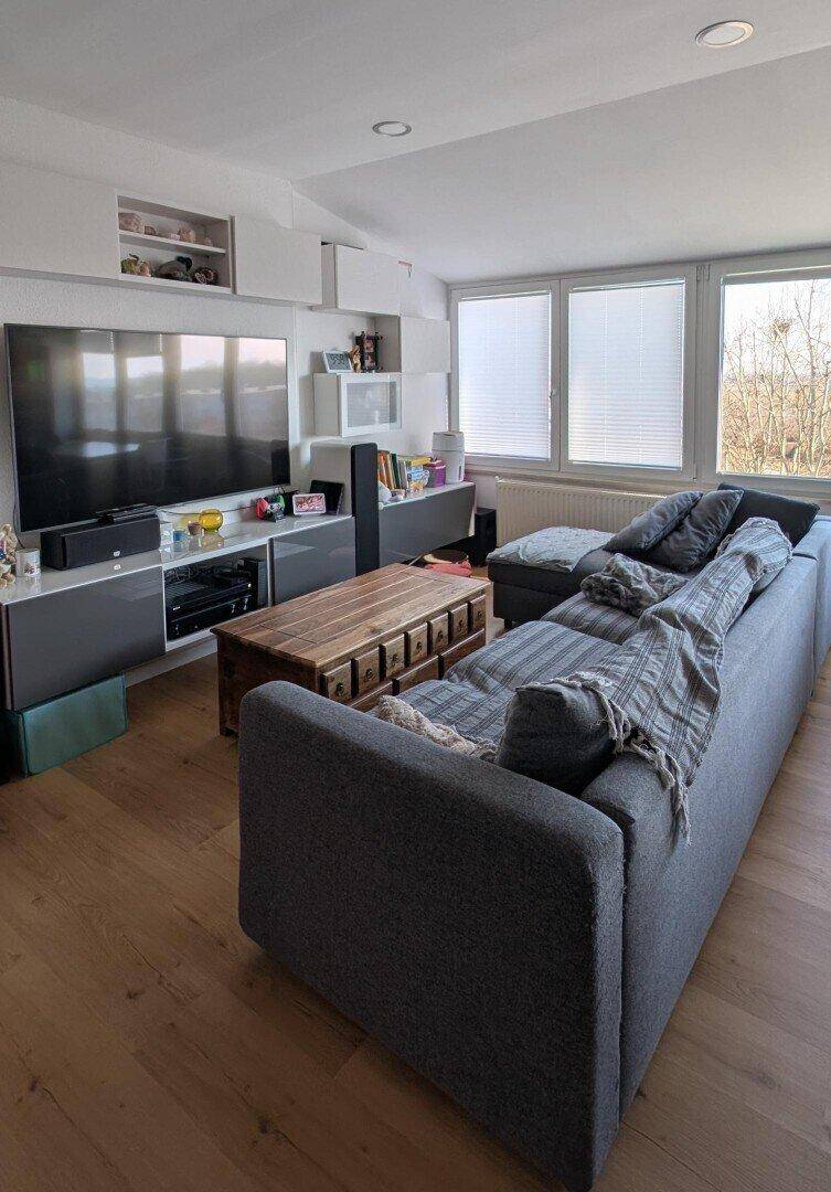 Gemütliches Wohnzimmer mit großem Sofa, Holzboden und Unterhaltungselektronik.