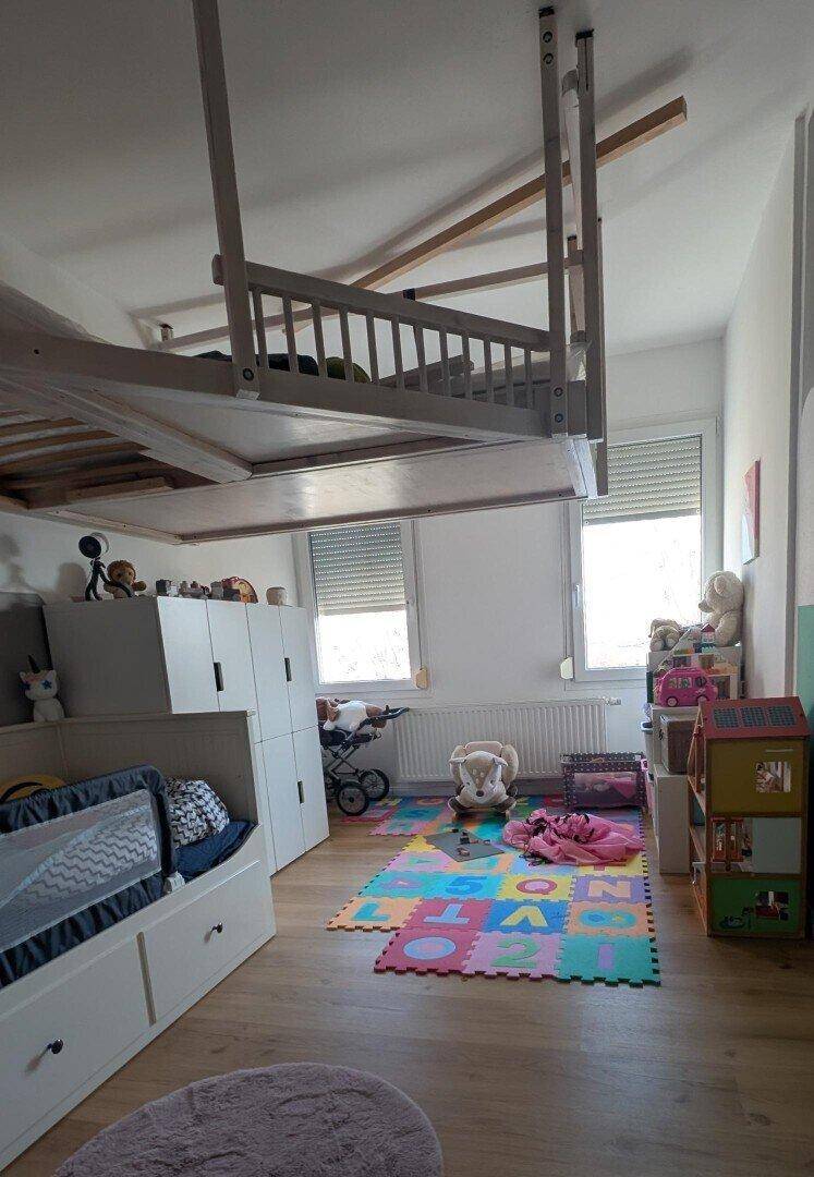 Helles Kinderzimmer mit Spielbereich, Holzboden und einem kreativen Hochbett.