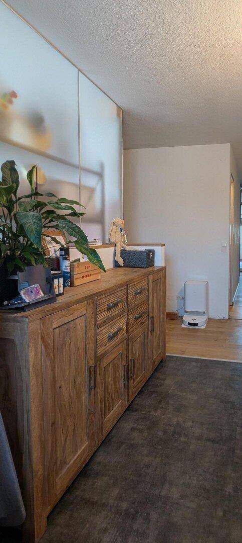 Heller Flur mit einem langen Holzschrank und Pflanzen als Dekoration.