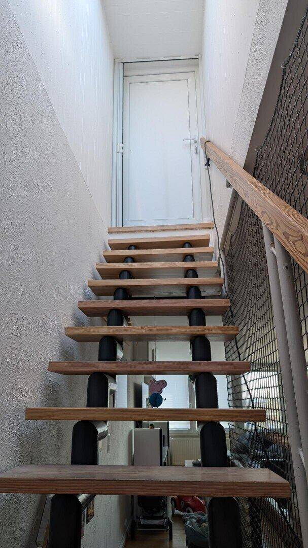 Offene Holztreppe mit Geländer und Zugang zu einer weiteren Etage.