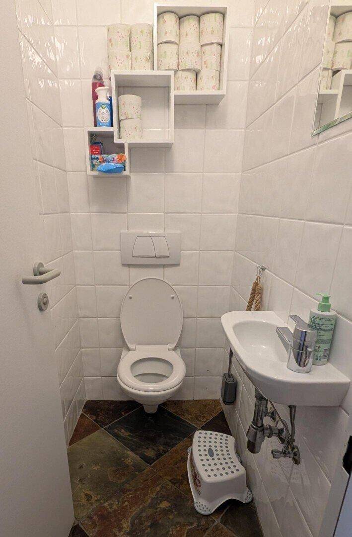 Kleines Gäste-WC mit Wand-WC, Waschbecken und gemusterten Fliesen.