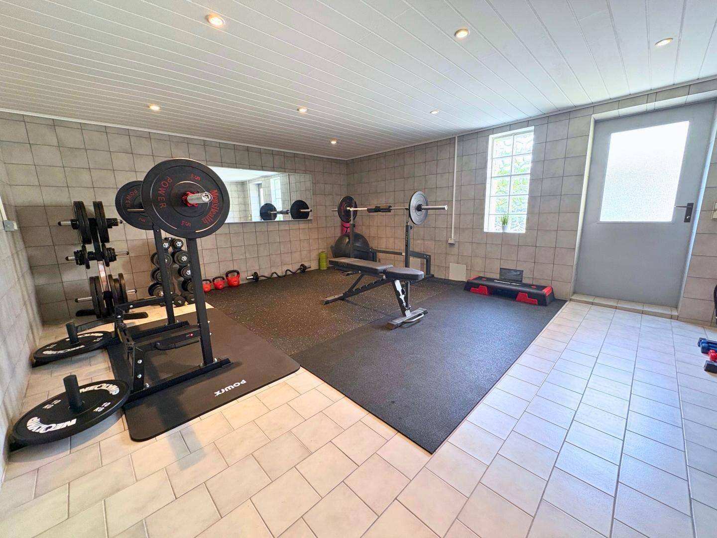 Gut ausgestatteter Fitnessraum mit Hanteln, Gewichten und Spiegelfläche.