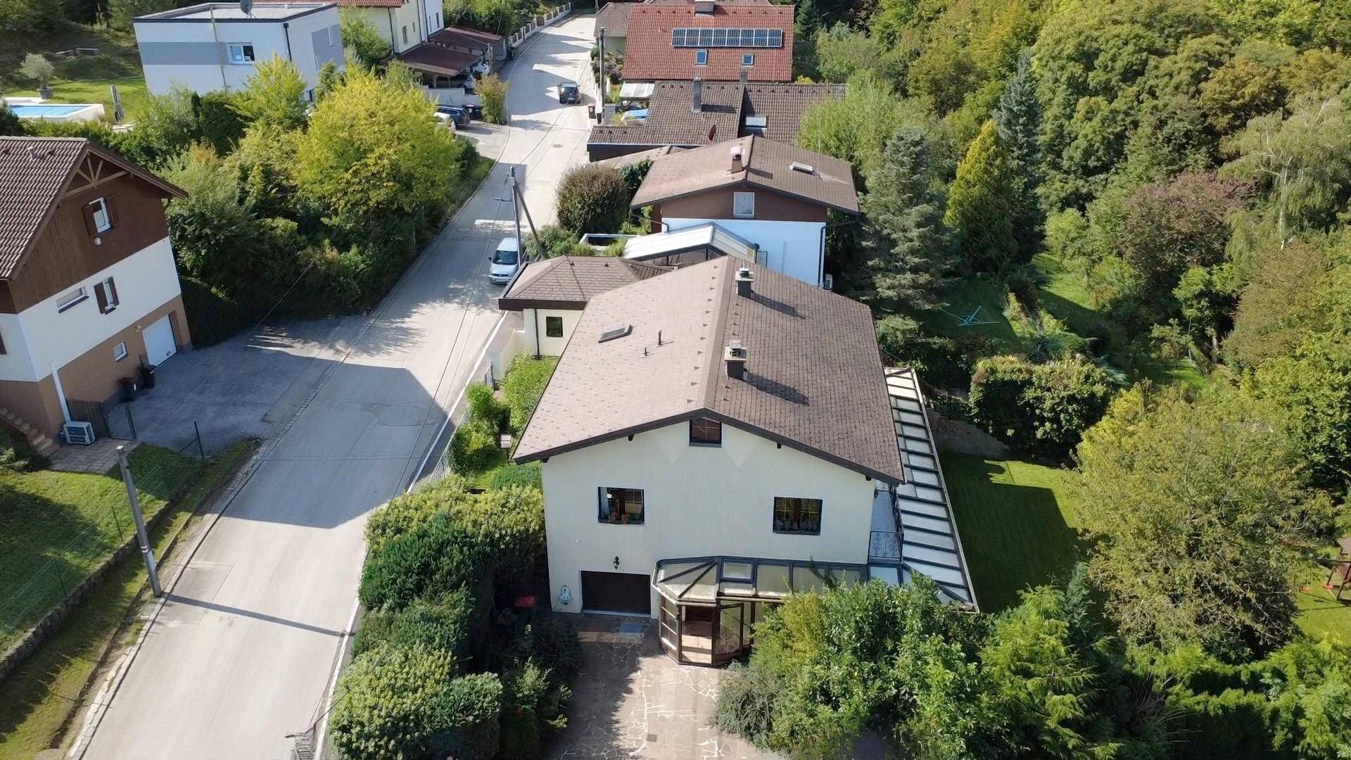 Luftaufnahme eines Einfamilienhauses mit Garten, Zufahrt und umliegender Wohnbebauung.
