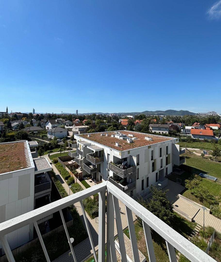 Weitblick vom Balkon über moderne Gebäude mit Gründächern und die umliegende Stadtlandschaft.