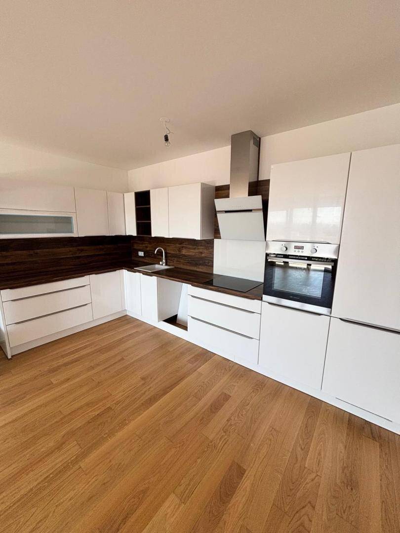 Moderne Einbauküche mit weißen Hochglanzfronten, Holzakzenten und integrierten Geräten.
