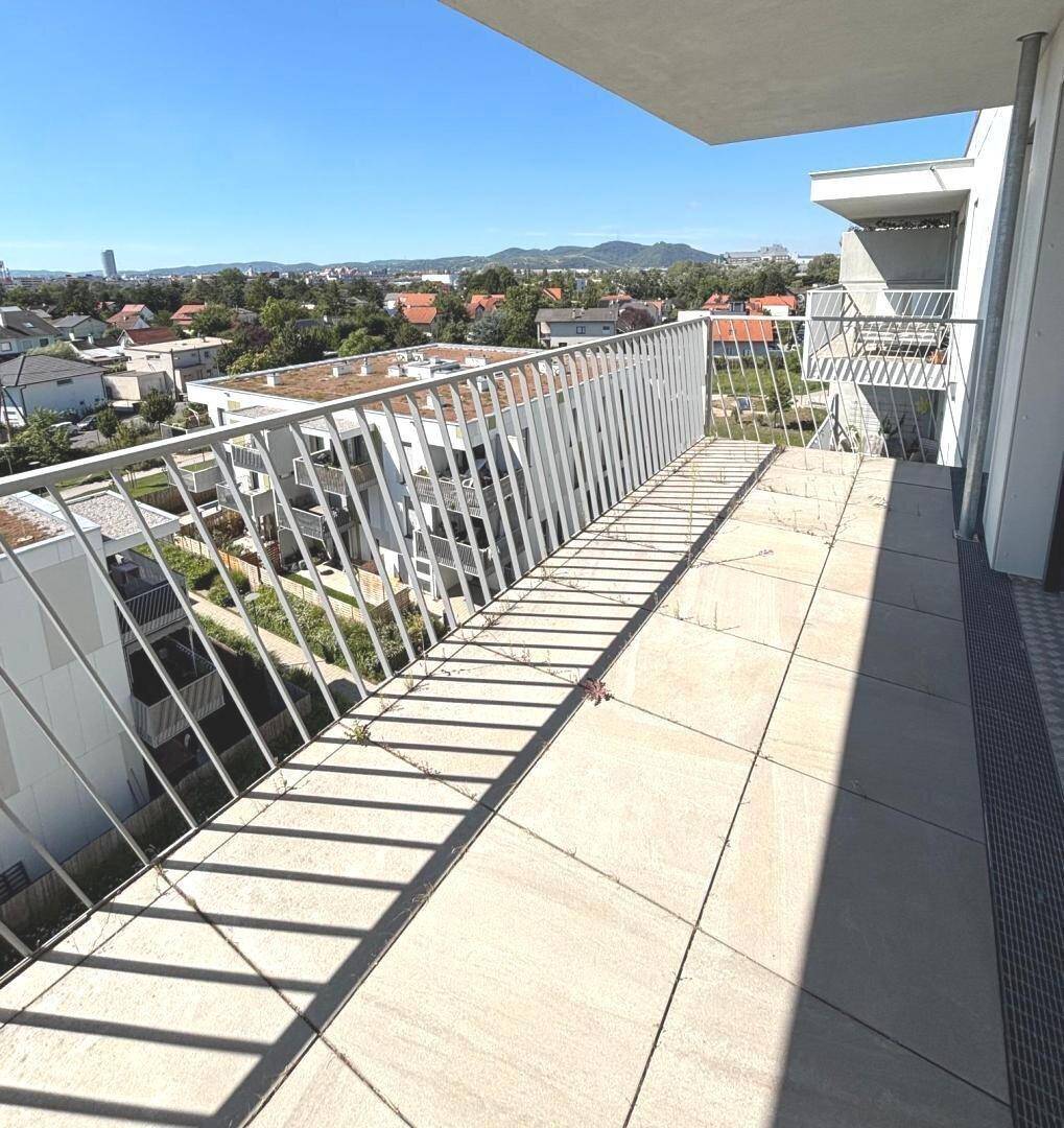 Geräumiger Balkon mit Fliesenboden und Metallgeländer, bietet einen weiten Blick über die Umgebung.