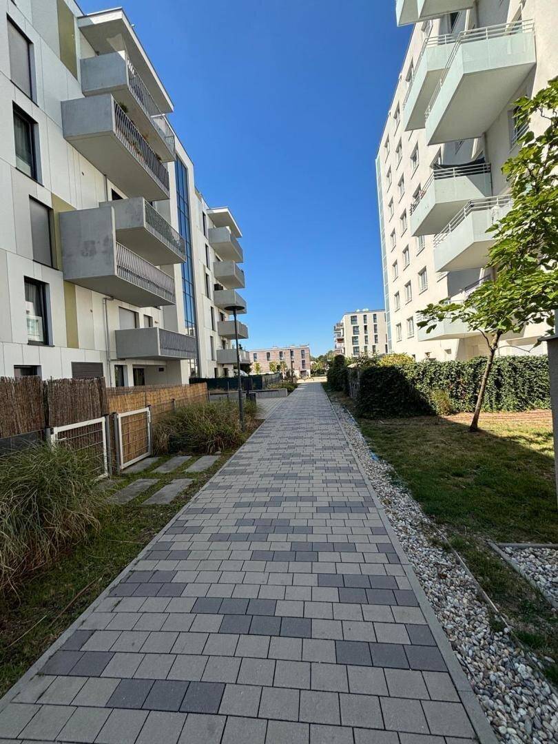 Gepflasterter Weg zwischen modernen Wohngebäuden mit begrünten Außenbereichen.