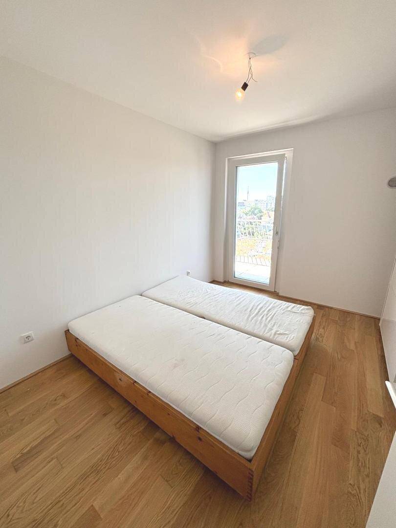 Helles Schlafzimmer mit Holzboden und Zugang zu einem Balkon oder einer Terrasse.