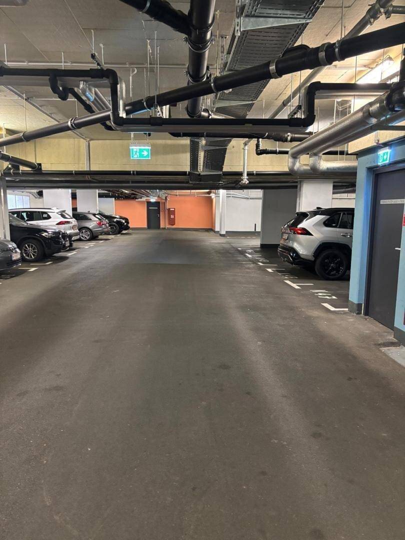 Tiefgarage mit mehreren Stellplätzen und sichtbaren Installationen an der Decke.