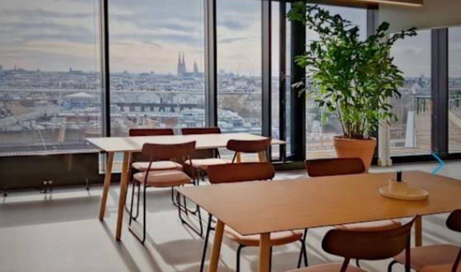 Heller Essbereich mit beeindruckendem Stadtblick, großen Fenstern und Pflanzen, ideal für Pausen oder informelle Meetings.