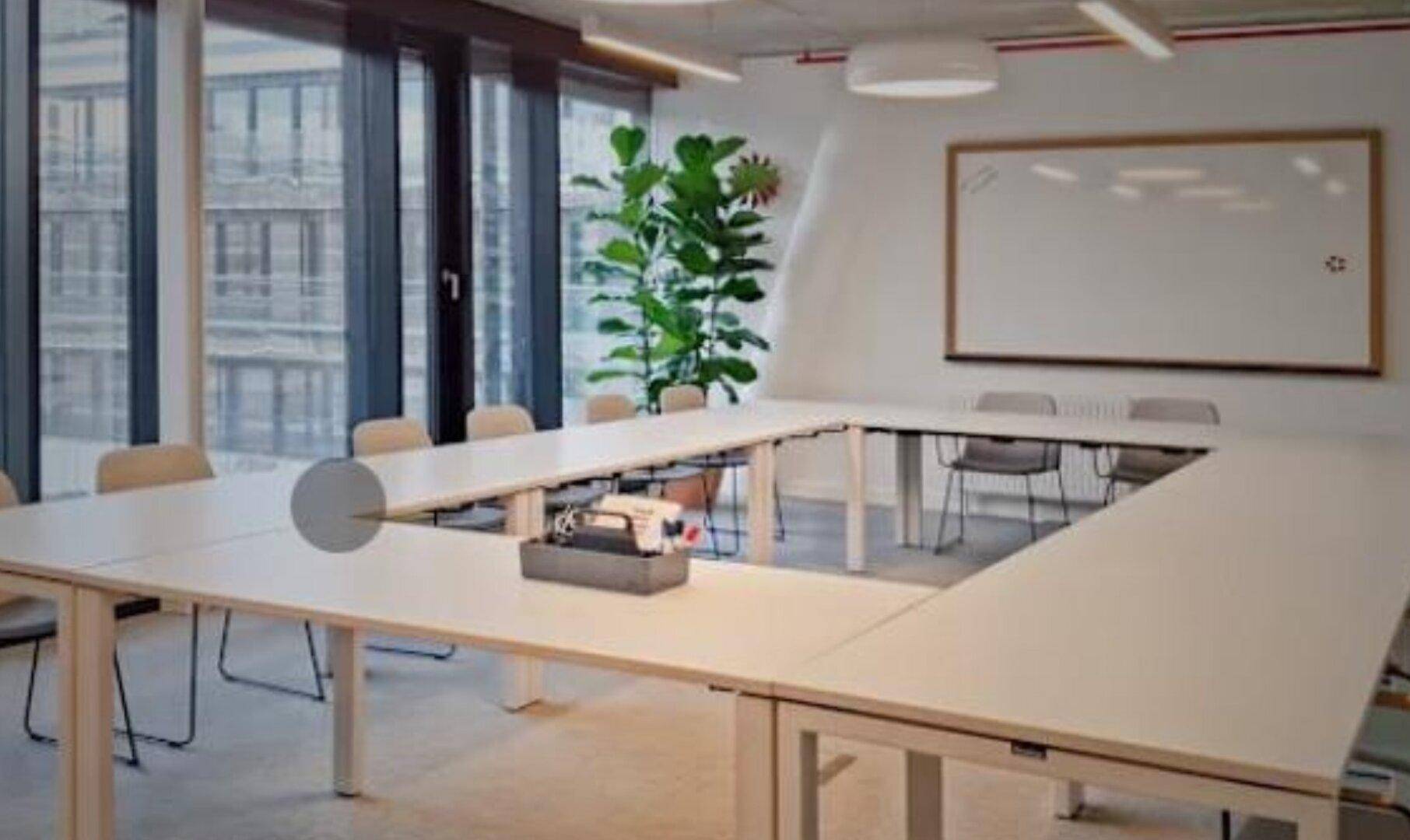 Großer Konferenzraum mit U-förmigem Tisch, vielen Stühlen und Blick auf die Stadt durch die Fenster für produktive Meetings.