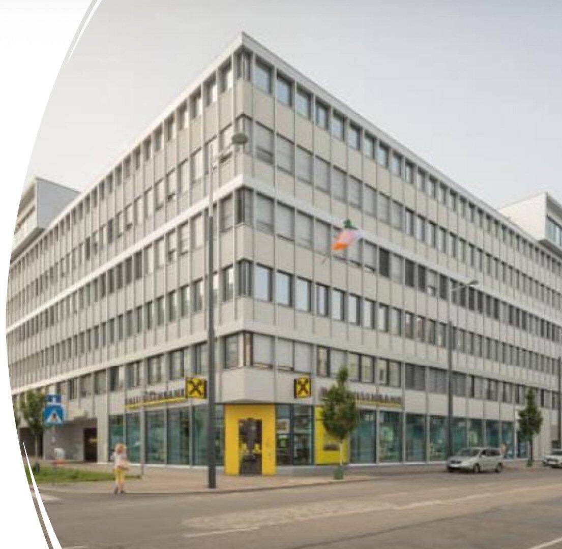 Großes Bürogebäude mit moderner Architektur, vielen Fenstern und einer Bankfiliale im Erdgeschoss an einer belebten Straße.
