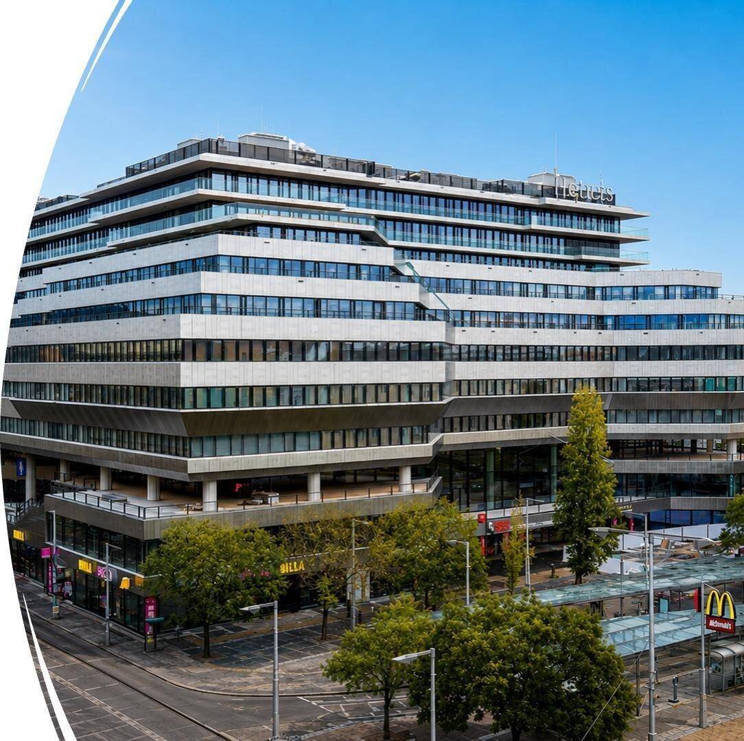 Großes, modernes Geschäftsgebäude mit gestufter Fassade und vielen Fenstern in urbaner Umgebung.