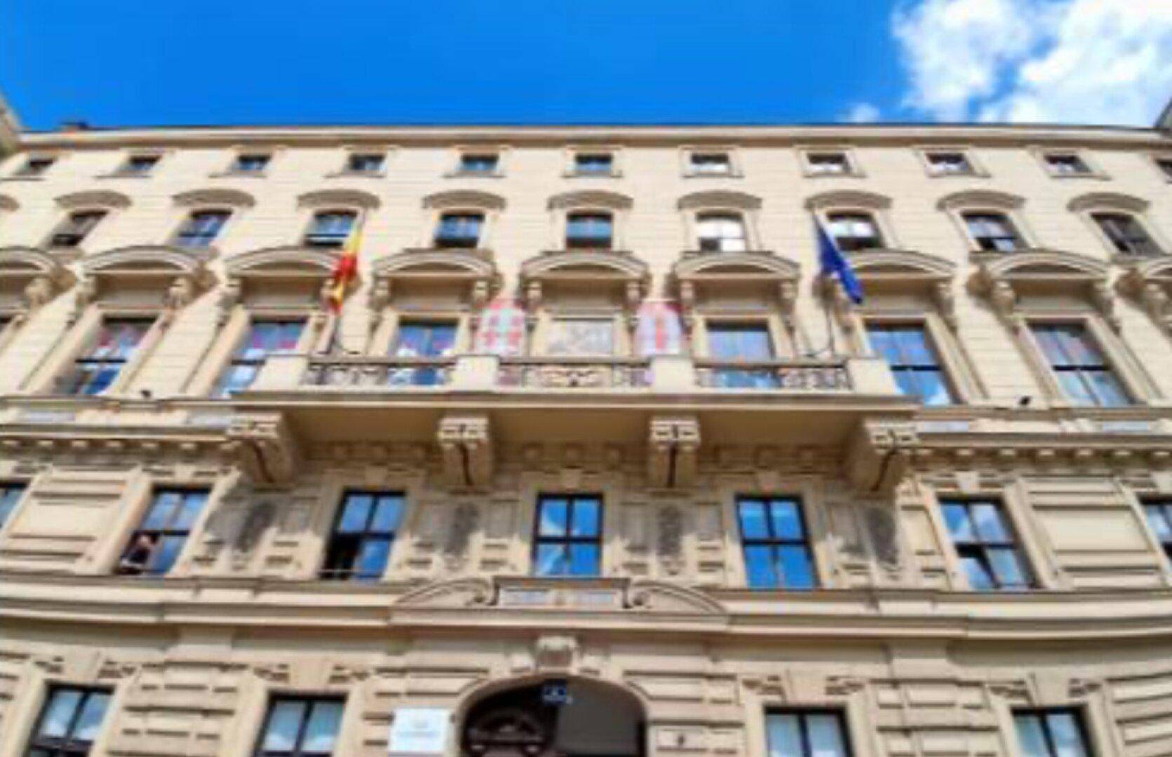 Klassische Gebäudefassade mit reich verzierten Balkonen und vielen Fenstern unter blauem Himmel.