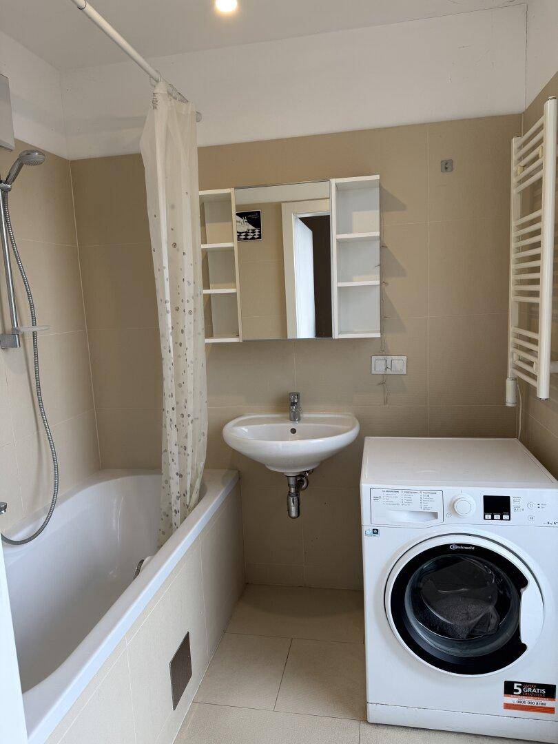 Badezimmer mit Badewanne, Waschbecken, Waschmaschine und beheiztem Handtuchhalter.