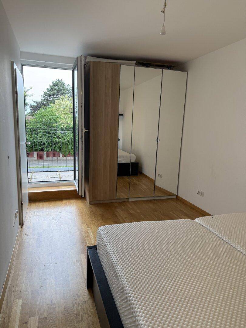 Geräumiges Schlafzimmer mit Holzboden, großem Kleiderschrank und Zugang zum Außenbereich.