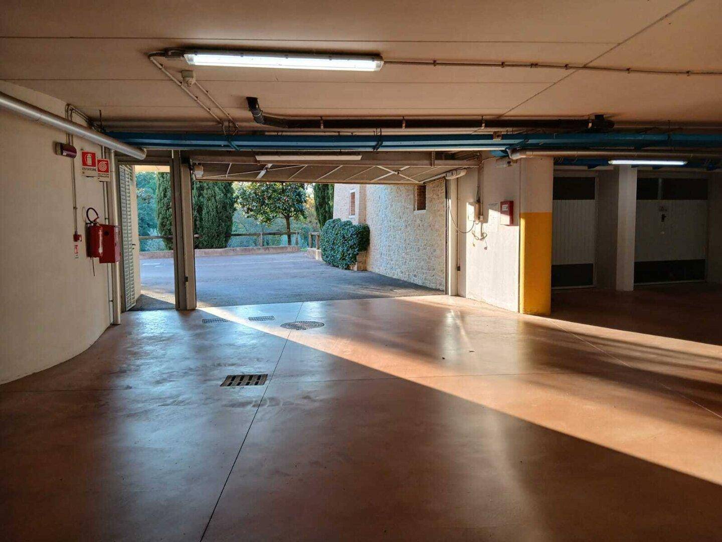 Eingangsbereich einer Tiefgarage mit Blick ins Freie und Betonboden.