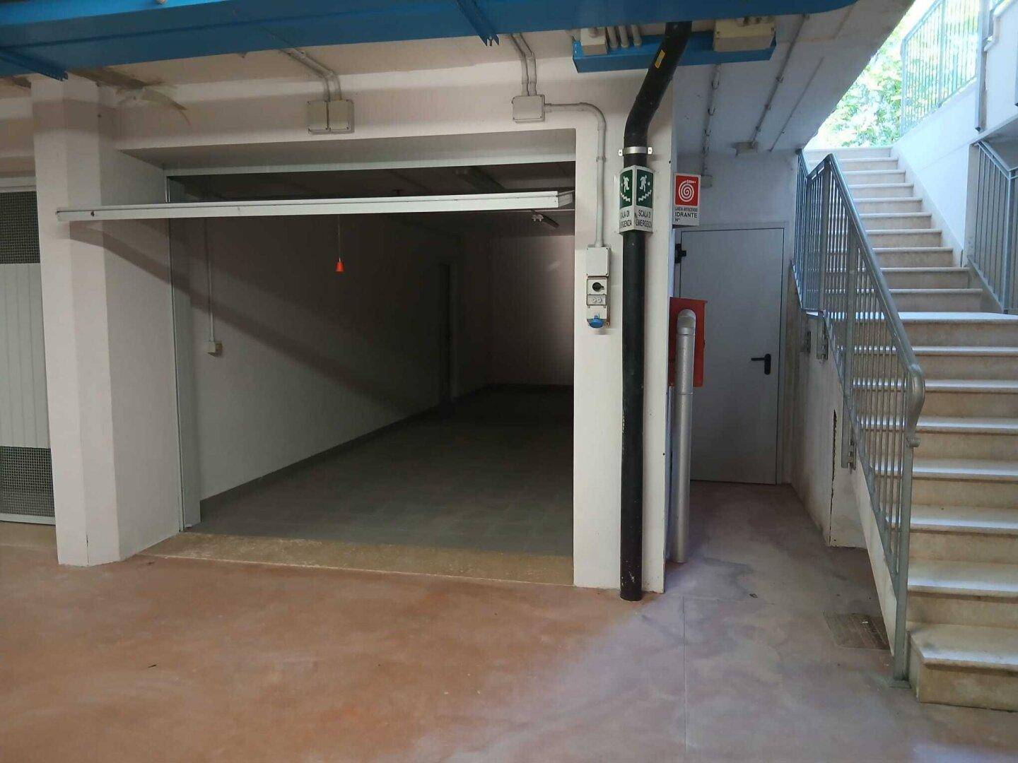 Einzelne Garagenbox in einer Tiefgarage mit Zugang zu einer Außentreppe.