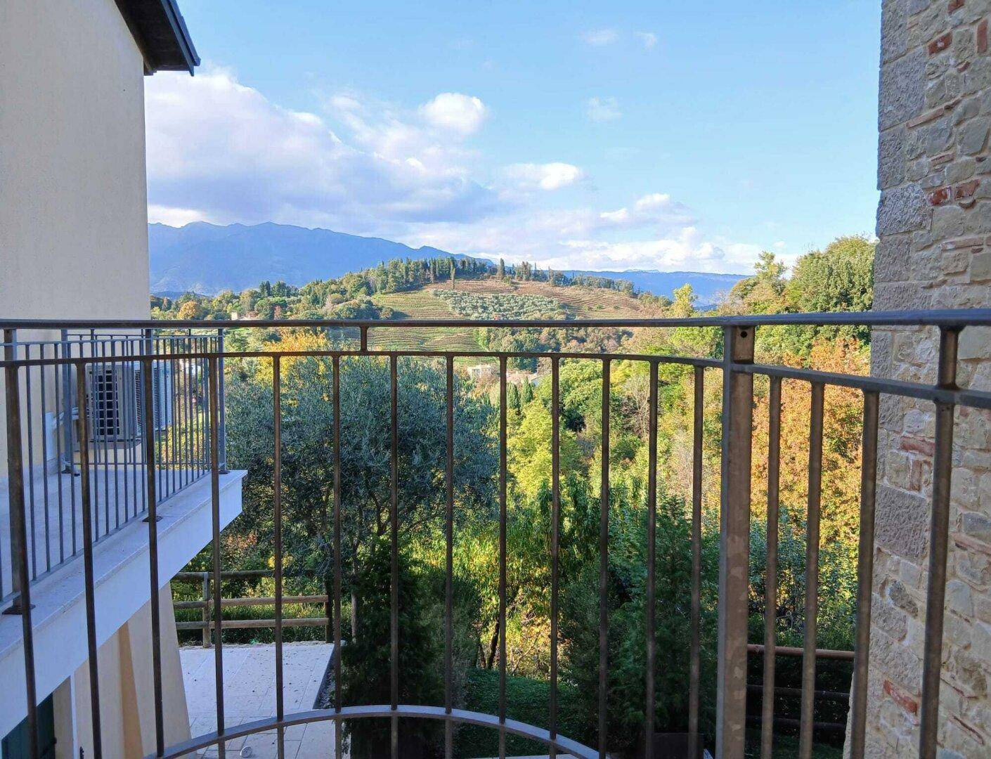 Balkon mit schmiedeeisernem Geländer und weitem Blick über die grüne Hügellandschaft.
