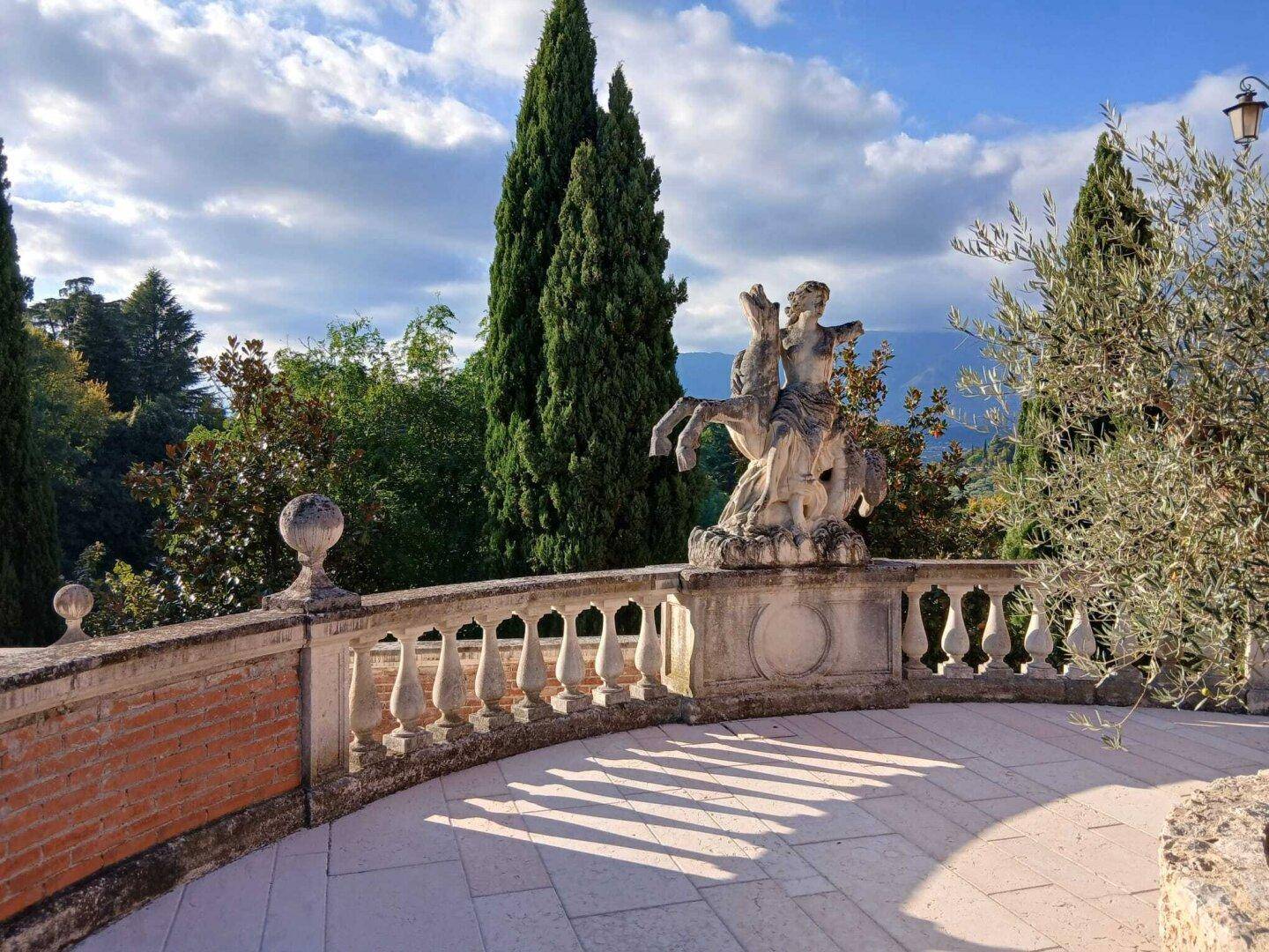 Große Steinterrasse mit klassischer Balustrade, Skulptur und weitem Blick auf die Landschaft.