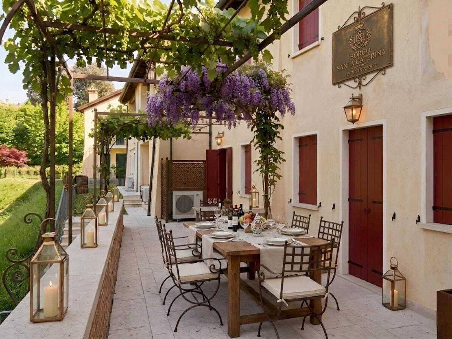Lange Terrasse mit Esstisch für mehrere Personen, Laternen und blühendem Blauregen.