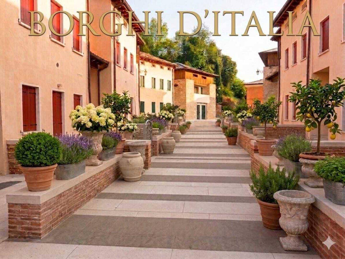 Malerische Gasse in einem italienischen Dorf mit blühenden Pflanzen und traditionellen Gebäuden.