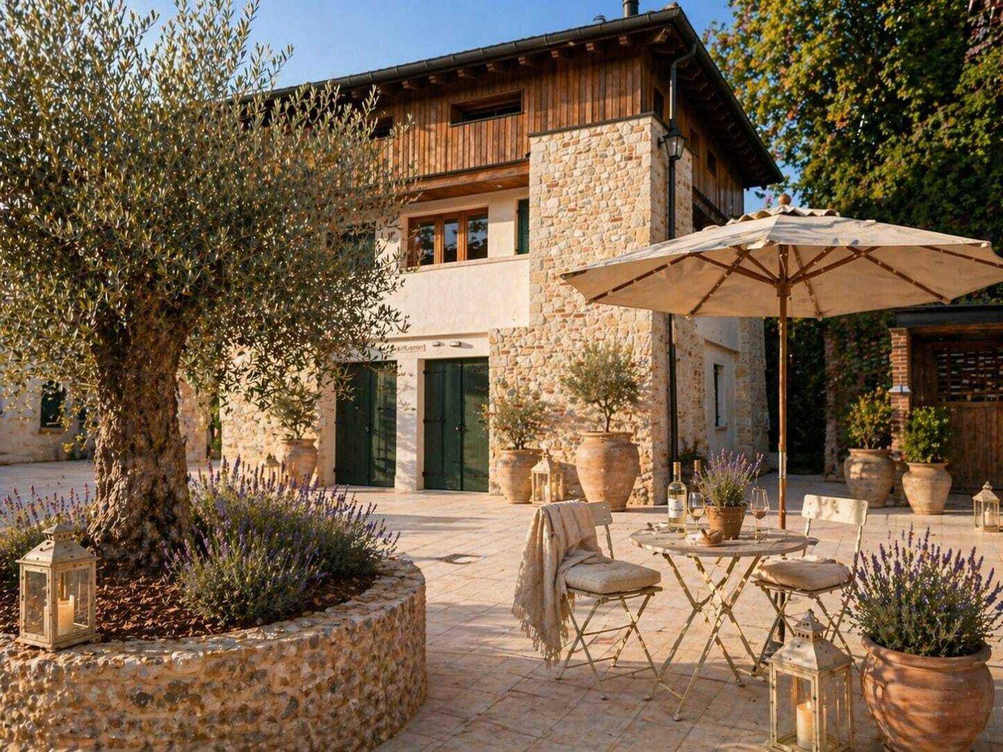 Mediterrane Villa mit Steinfassade, Holzelementen und einer gemütlichen Terrasse mit Olivenbaum.