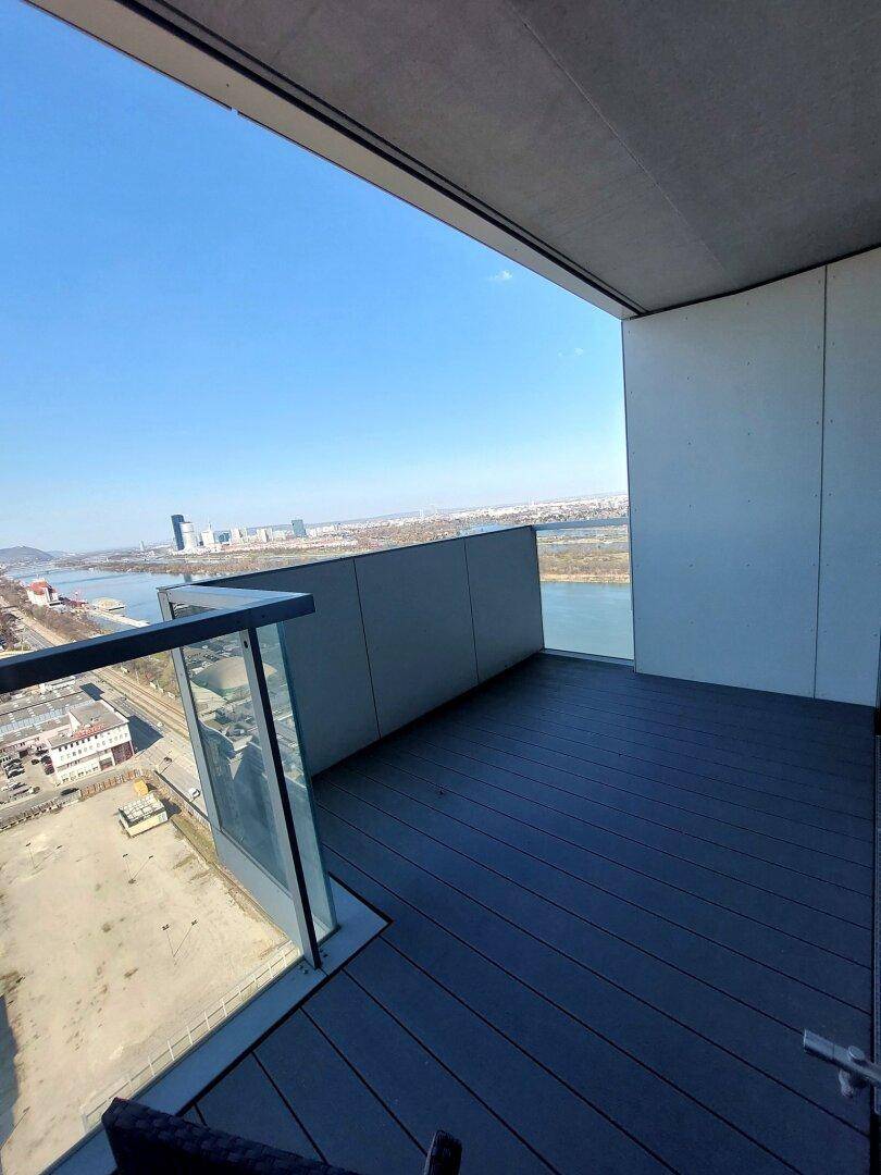 Geräumiger Balkon mit modernen Dielen und atemberaubendem Blick über die Stadt und die Donau.